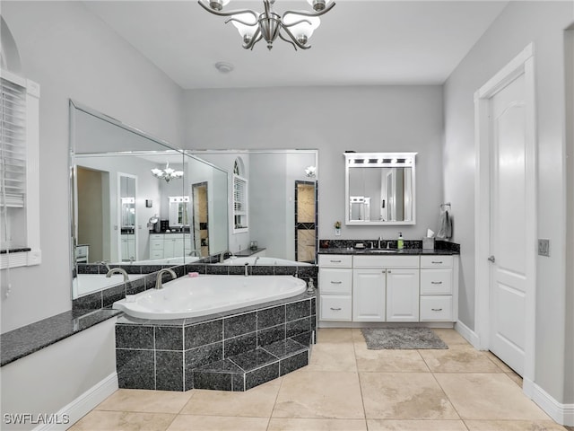 bathroom featuring tile patterned floors, vanity, tiled bath, and a notable chandelier