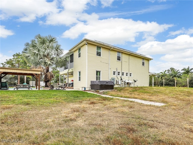 back of house with a patio area, a yard, and a hot tub