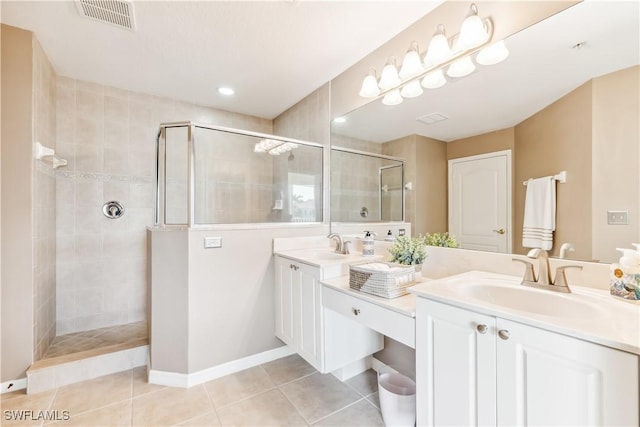 bathroom with double vanity, visible vents, a sink, tile patterned flooring, and tiled shower