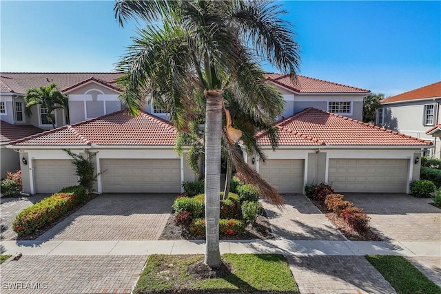 mediterranean / spanish-style home with decorative driveway, an attached garage, and stucco siding