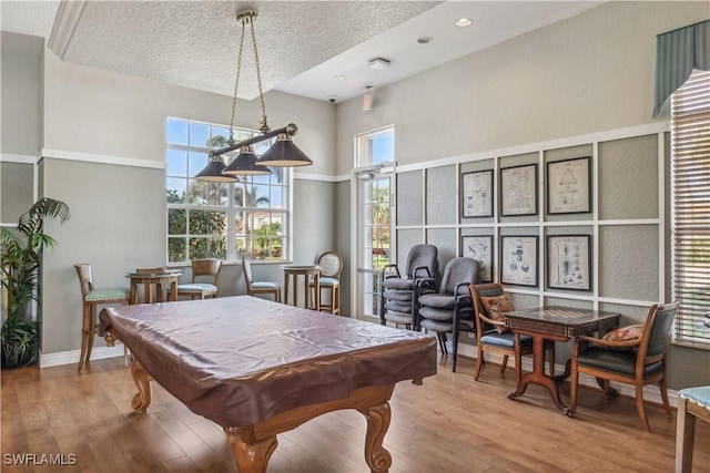 game room with billiards, baseboards, a high ceiling, a textured ceiling, and light wood-type flooring