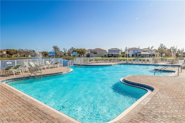 community pool with a residential view, fence, and a patio