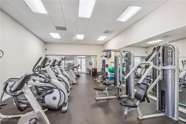 gym with a drop ceiling and baseboards