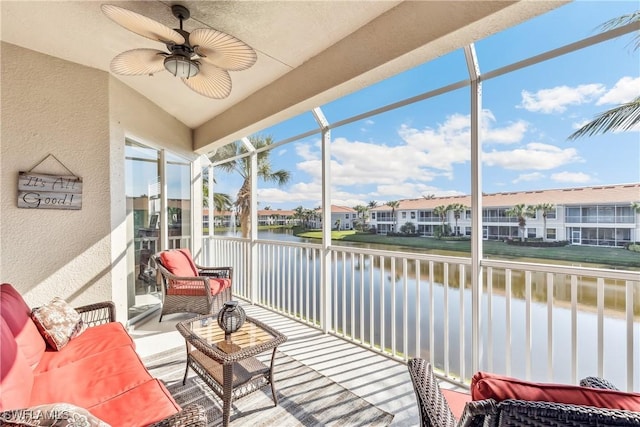 sunroom featuring a residential view, a water view, and ceiling fan