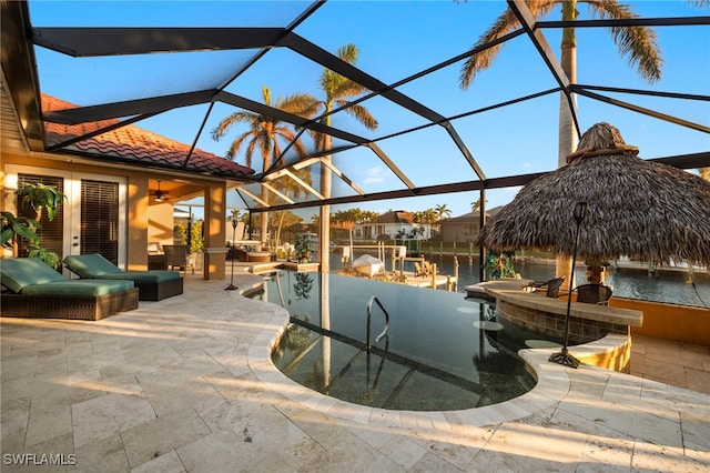 view of pool featuring glass enclosure, a water view, exterior bar, and a patio