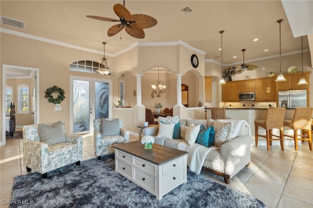 living room with ornate columns, ceiling fan, a high ceiling, crown molding, and light tile patterned floors