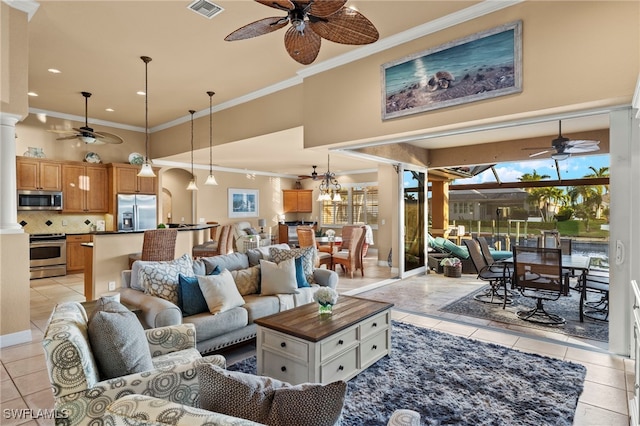 tiled living room featuring ceiling fan with notable chandelier, decorative columns, and crown molding