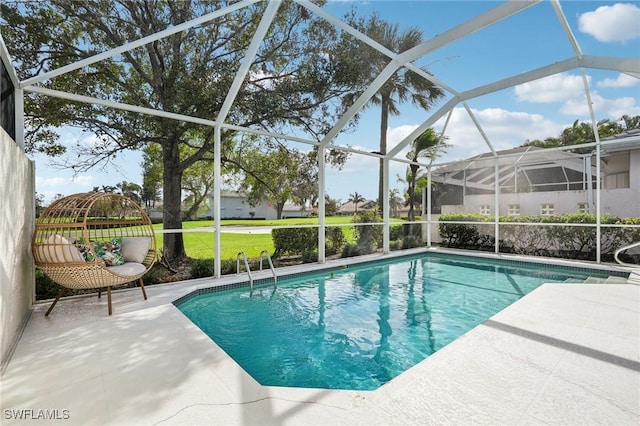 view of pool with a lawn, glass enclosure, and a patio