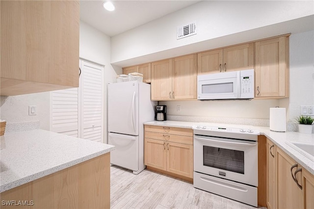 kitchen featuring white appliances, light brown cabinetry, and light hardwood / wood-style flooring