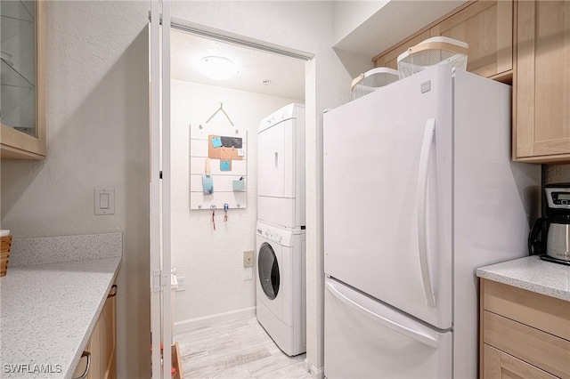 laundry room featuring light hardwood / wood-style flooring and stacked washer / drying machine