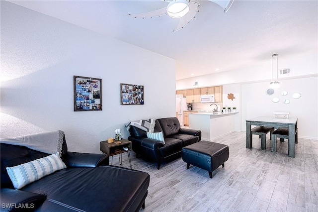 living room featuring light hardwood / wood-style floors, ceiling fan, and sink