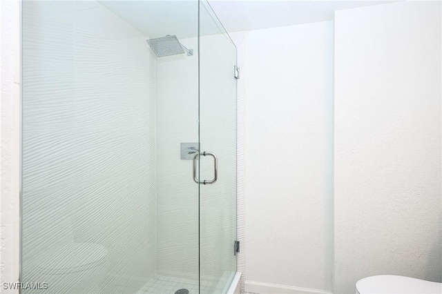 bathroom with toilet and a shower with door