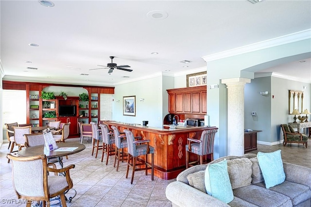 interior space with ornate columns, ceiling fan, and ornamental molding