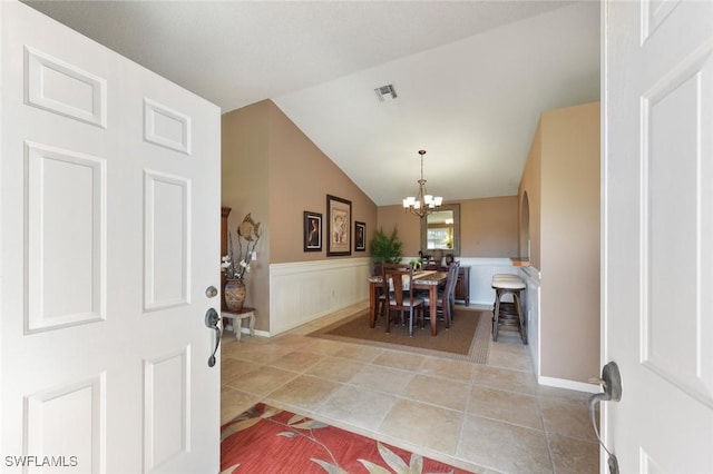 entrance foyer with an inviting chandelier, light tile patterned floors, and vaulted ceiling