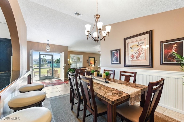 dining space featuring tile patterned floors, a textured ceiling, and a chandelier