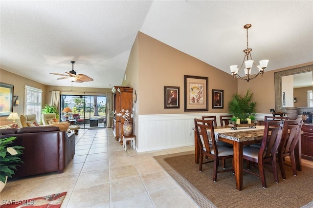 dining space featuring ceiling fan with notable chandelier, lofted ceiling, and light tile patterned floors