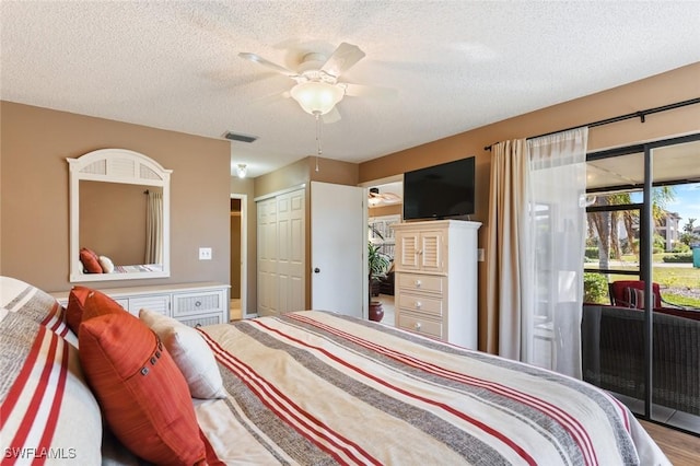 bedroom with access to exterior, a textured ceiling, ceiling fan, wood-type flooring, and a closet