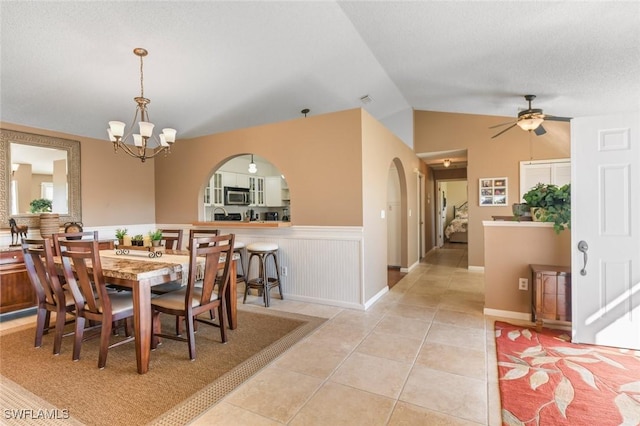 dining room featuring ceiling fan with notable chandelier, light tile patterned floors, and vaulted ceiling