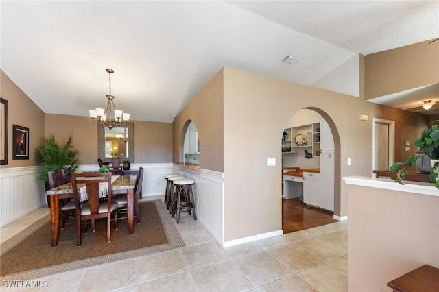 dining space with lofted ceiling, light tile patterned floors, and a chandelier