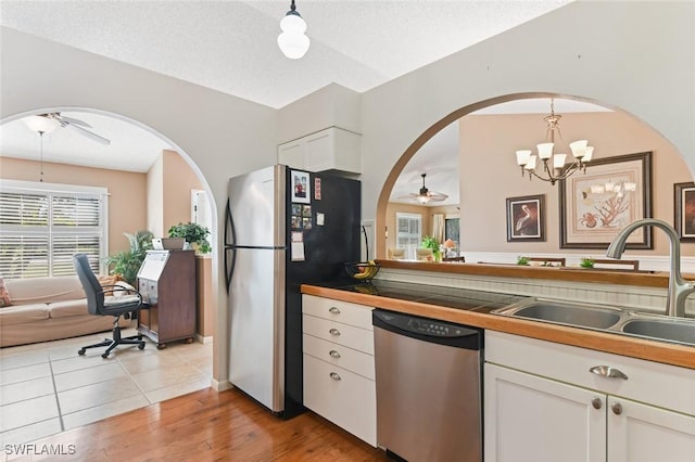 kitchen featuring white cabinetry, sink, hanging light fixtures, stainless steel appliances, and ceiling fan with notable chandelier