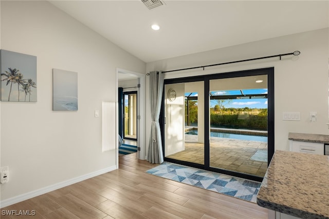 doorway to outside featuring light hardwood / wood-style floors and lofted ceiling