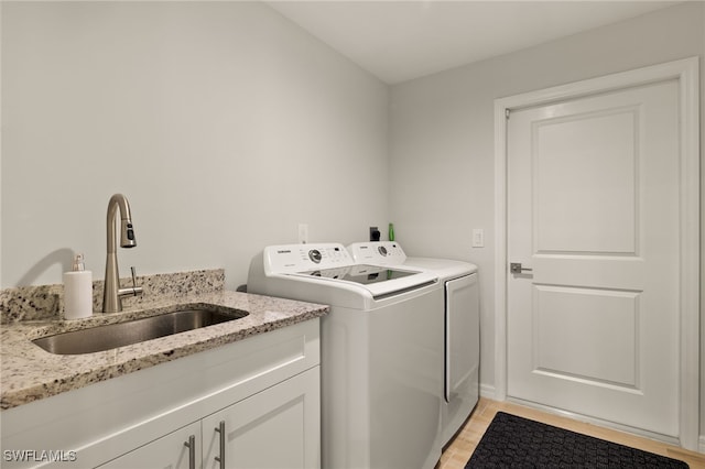 clothes washing area with cabinets, sink, and washer and dryer