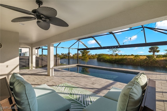 view of patio / terrace featuring a lanai, ceiling fan, a water view, and an outdoor hangout area