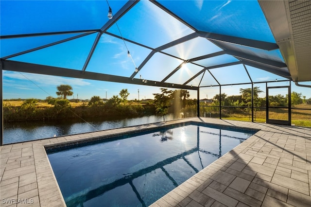 view of swimming pool featuring glass enclosure, a patio area, and a water view