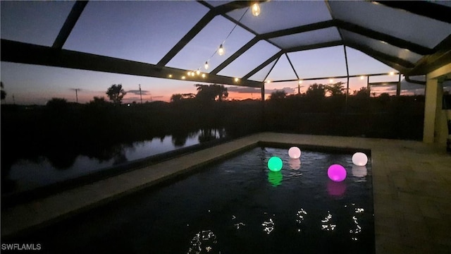 pool at dusk with a water view and glass enclosure