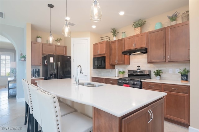 kitchen with sink, decorative light fixtures, a kitchen island with sink, and black appliances