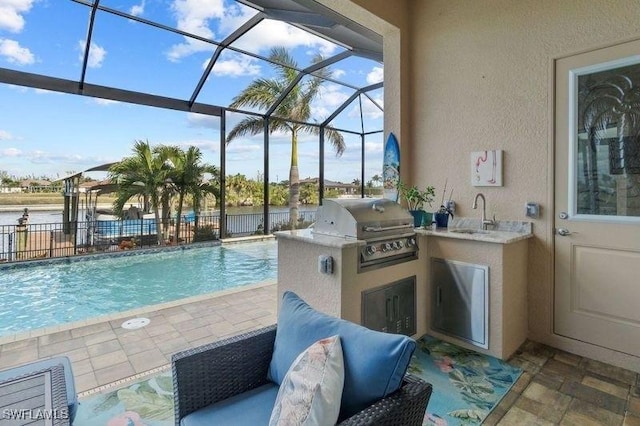 view of swimming pool with sink, exterior kitchen, glass enclosure, grilling area, and a patio