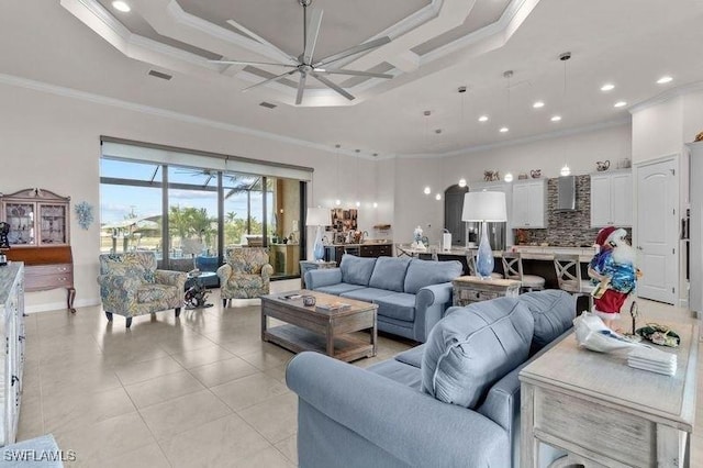 living room featuring ceiling fan, ornamental molding, light tile patterned floors, and a tray ceiling