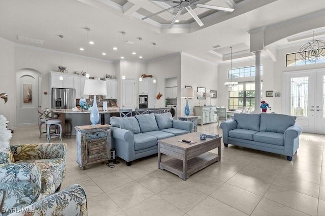 living room featuring coffered ceiling, a high ceiling, light tile patterned flooring, ceiling fan with notable chandelier, and ornamental molding