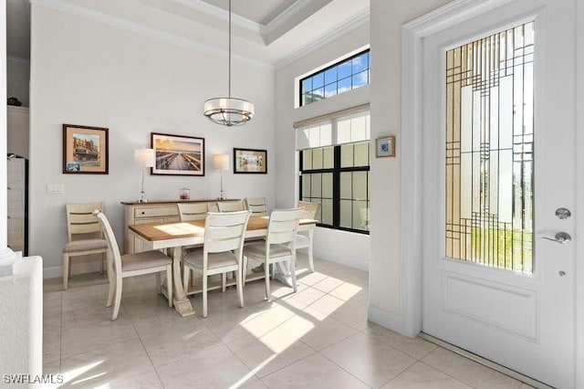 tiled dining area with ornamental molding, a high ceiling, and a chandelier