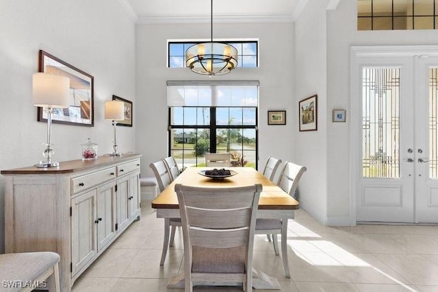 tiled dining space featuring a high ceiling, an inviting chandelier, french doors, and ornamental molding