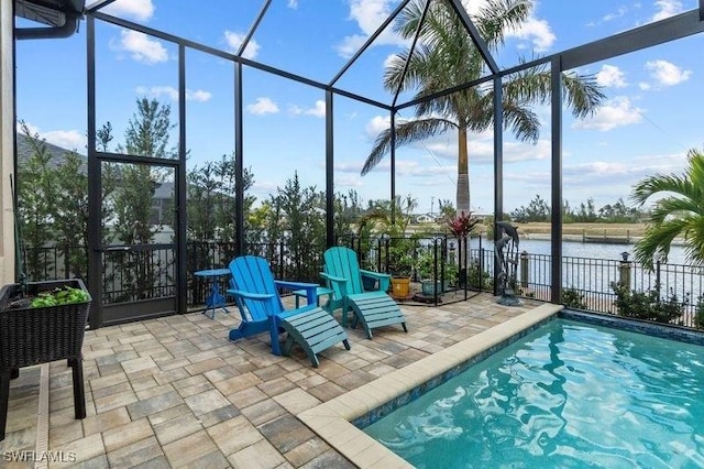 view of swimming pool with a water view, glass enclosure, and a patio area