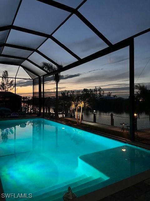 pool at dusk with glass enclosure and a water view