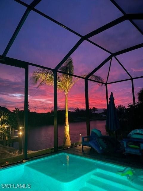 pool at dusk featuring glass enclosure and a water view