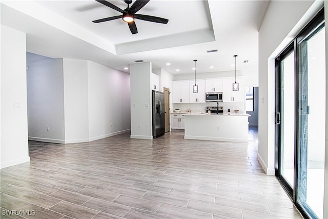 unfurnished living room with a tray ceiling and ceiling fan