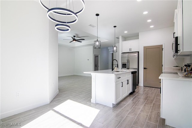 kitchen featuring sink, white cabinetry, hanging light fixtures, stainless steel appliances, and a kitchen island with sink