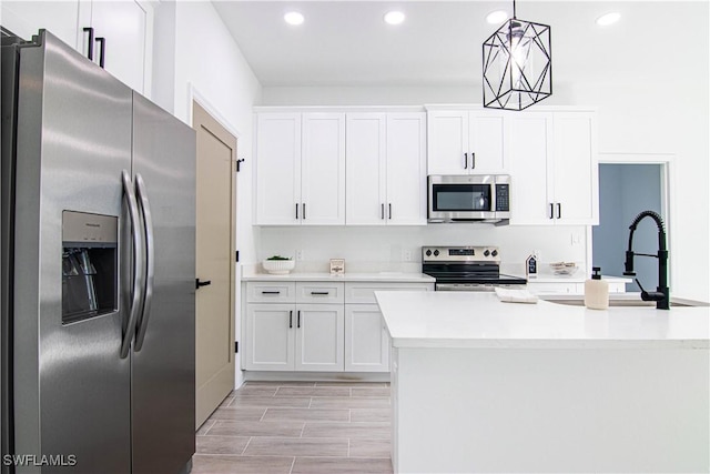 kitchen with white cabinetry, appliances with stainless steel finishes, sink, and decorative light fixtures