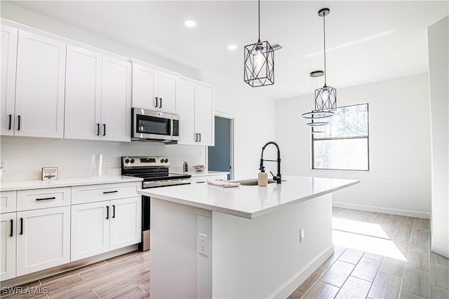 kitchen with white cabinetry, appliances with stainless steel finishes, a kitchen island with sink, and sink