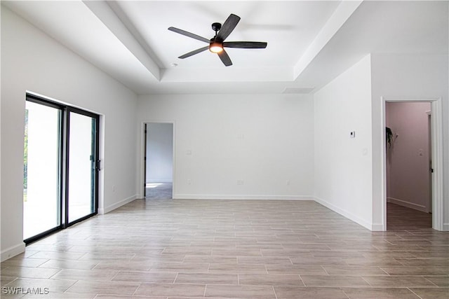 empty room with a raised ceiling and ceiling fan