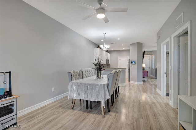 dining area featuring light hardwood / wood-style floors and ceiling fan with notable chandelier