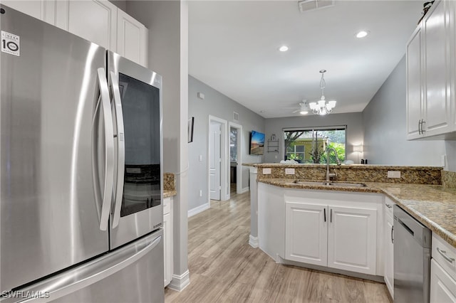 kitchen featuring kitchen peninsula, light wood-type flooring, stainless steel appliances, sink, and white cabinetry