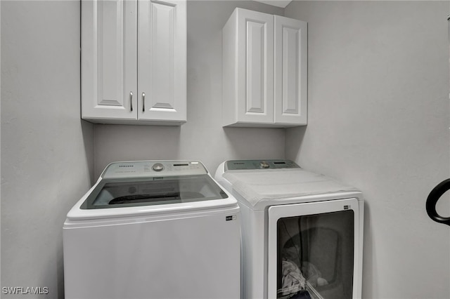 washroom with washer and dryer and cabinets