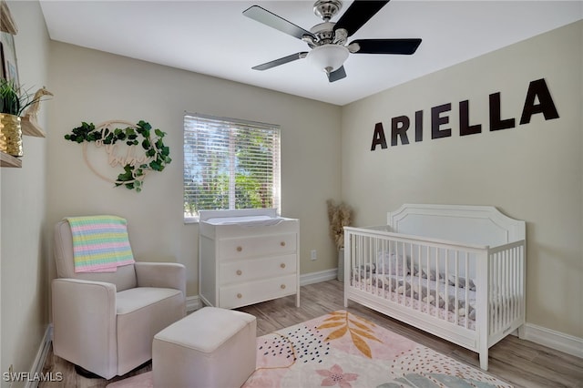 bedroom with ceiling fan, light wood-type flooring, and a nursery area