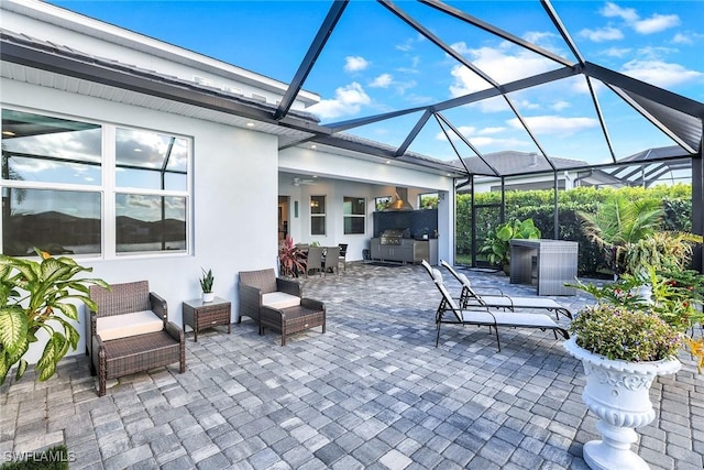 view of patio / terrace with glass enclosure, ceiling fan, and exterior kitchen