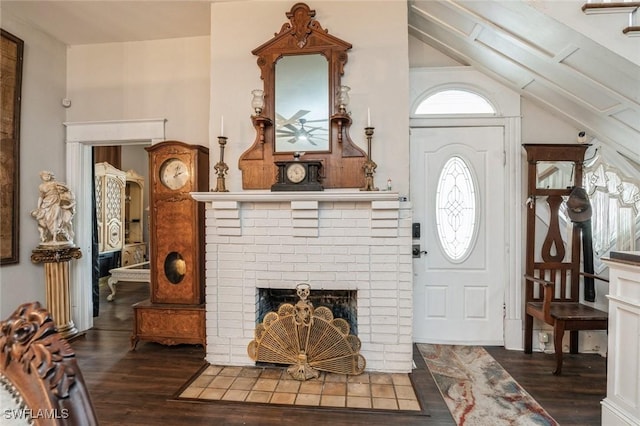 foyer featuring lofted ceiling, dark hardwood / wood-style floors, and a brick fireplace