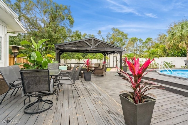 wooden terrace featuring a gazebo, a fenced in pool, and a storage shed